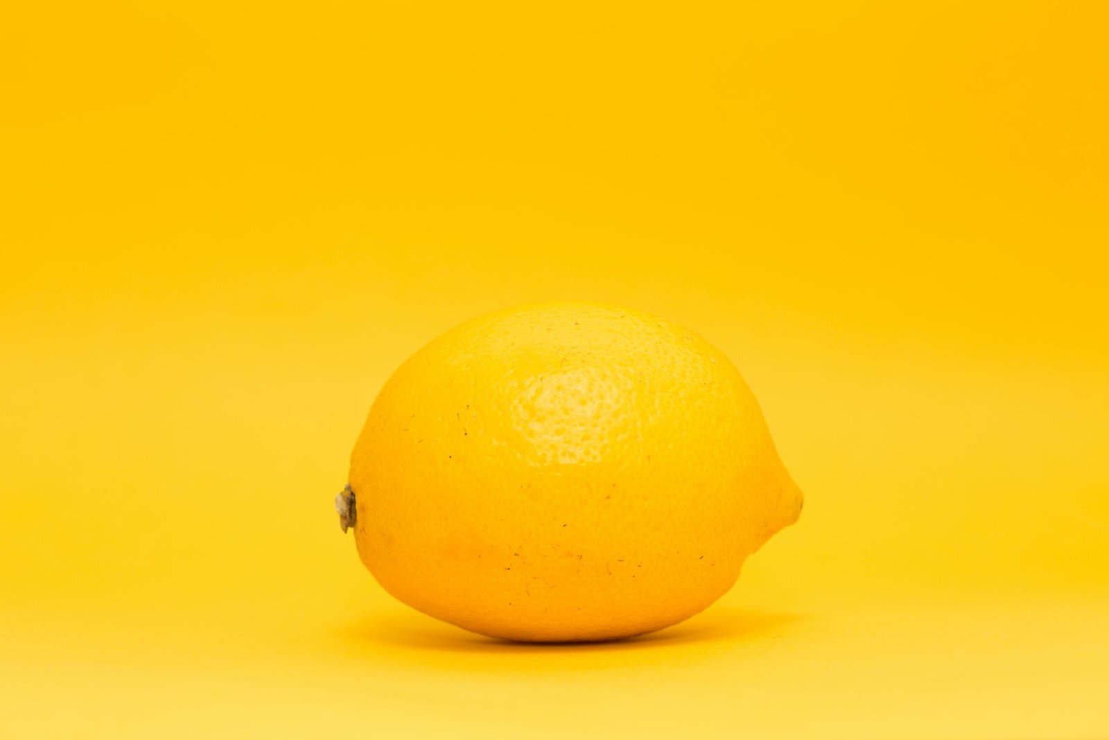Bright lemon showcased on a uniform yellow backdrop, highlighting freshness and citrus appeal.