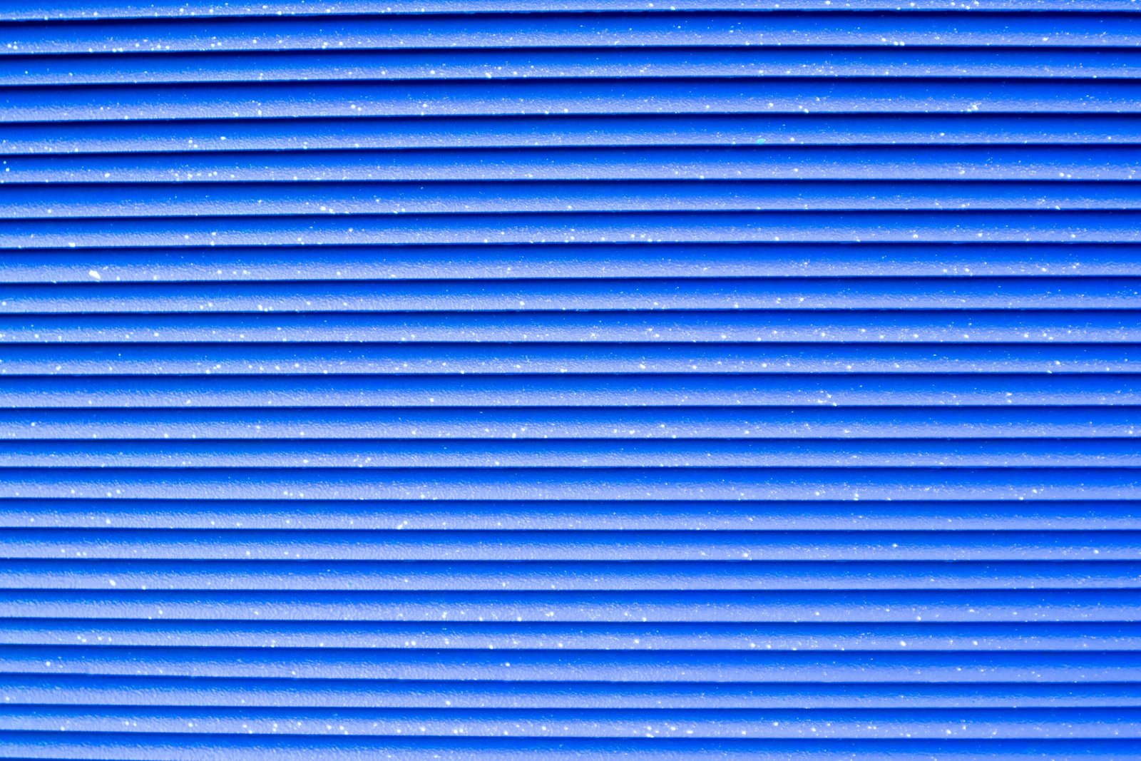 Close-up of a vibrant blue corrugated metal texture with repetitive patterns.